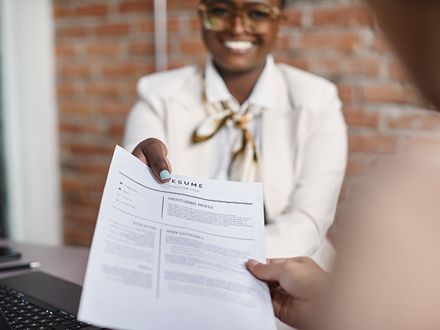 Close-up of young black businesswoman gives her resume during job interview in the office.